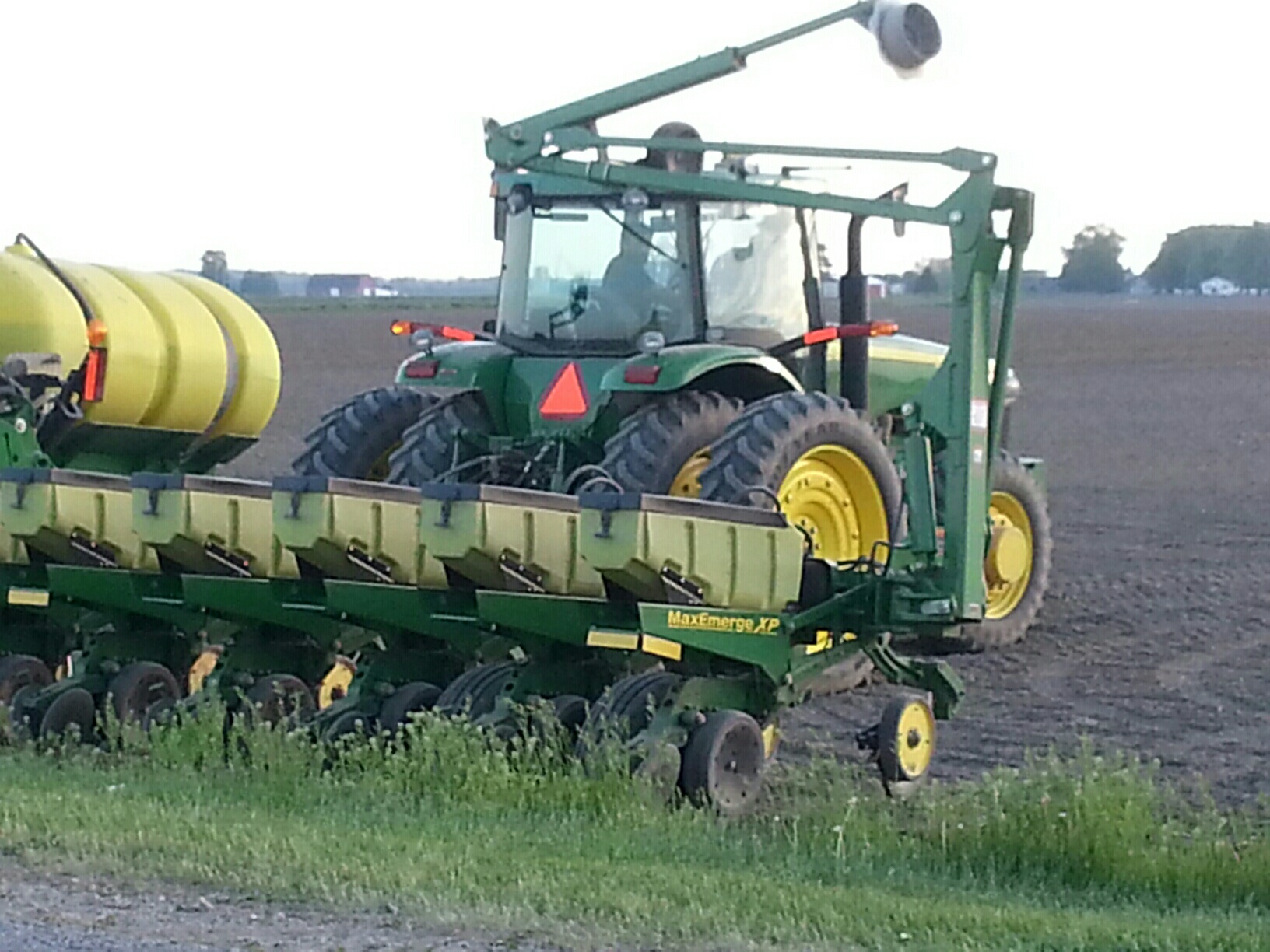 Tractor planting seeds in a vast field.