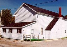 White building with dark roof and chimney, sunny day.